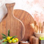 front-view-cutting-board-wooden-spoons-grater-kumquats-pot-colorful-surface (1)